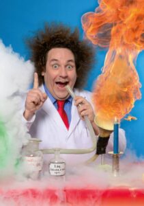 Das Bild zeigt Comedian Konrad Stoeckel mit seiner verrückten Wissenschaftsshow. Flammen und Rauch sind in Stöckels Labor zu sehen.