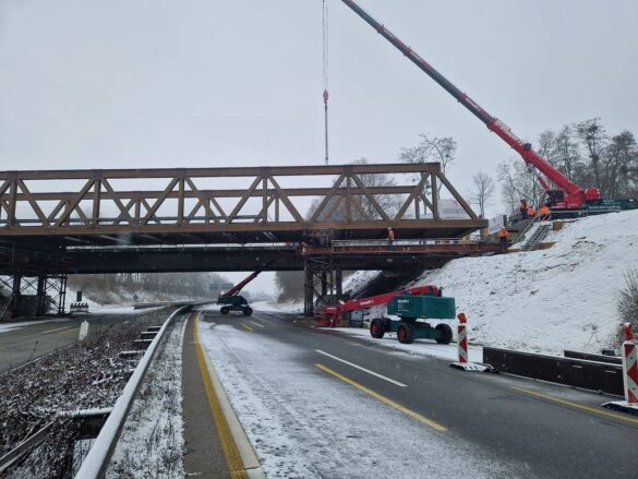 56aktuell_84JYIy5G Bauarbeiten an einer Brücke über einer verschneiten Autobahn.