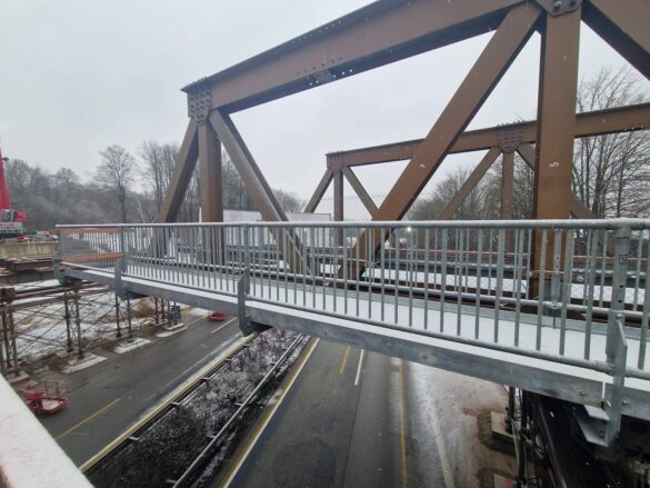 56aktuell_LHzWh3lm Brücke mit Metallgeländer über eine Straße im Winter