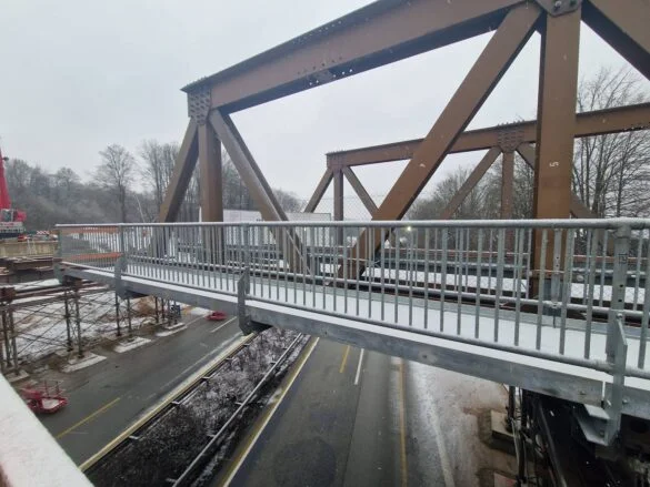 56aktuell_LHzWh3lm Brücke mit Metallgeländer über eine Straße im Winter