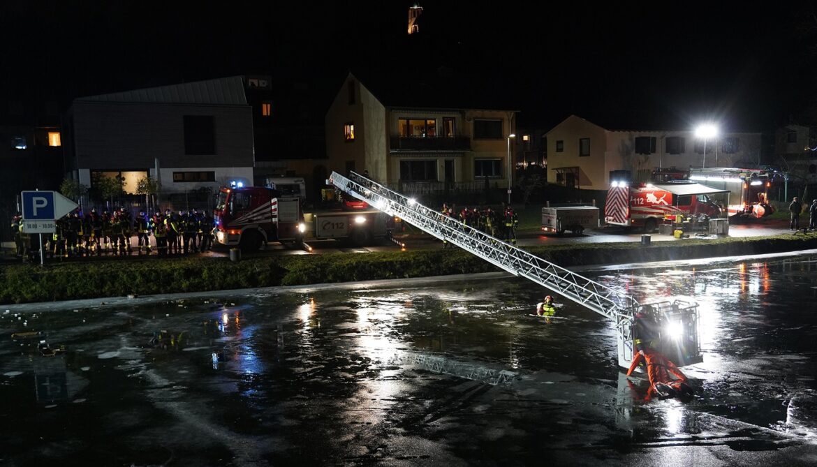 Feuerwehr im Einsatz bei Nacht auf einem zugefrorenen Schleusenkanal.