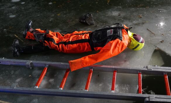 56aktuell_bwVA3eBZ Person in orange suit liegt auf Eis neben einer Leiter.
