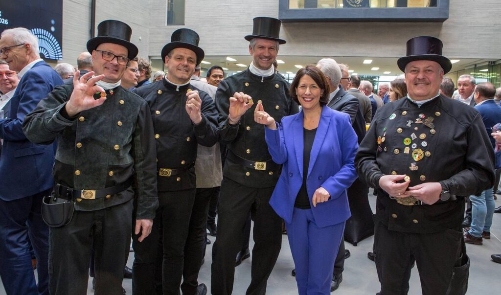 Gruppe von Schornsteinfegern mit einer Frau in einem blauen Anzug bei einer Veranstaltung. Die Frau ist die rheinland-pfälzische Wirtschaftsministerin Daniela Schmitt.