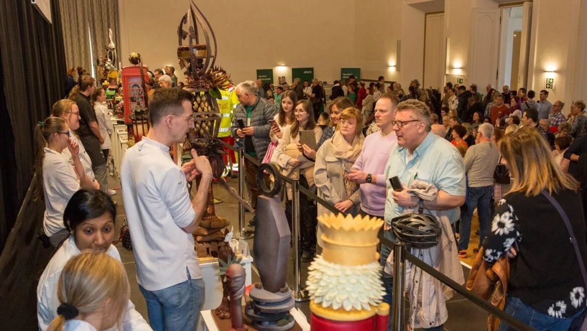 Menschen bewundern Schokoladenkunstwerke auf einer Ausstellung.
