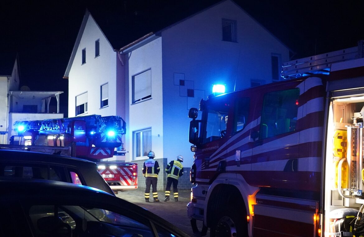 Feuerwehrfahrzeuge und Einsatzkräfte bei Nacht vor einem Wohnhaus.