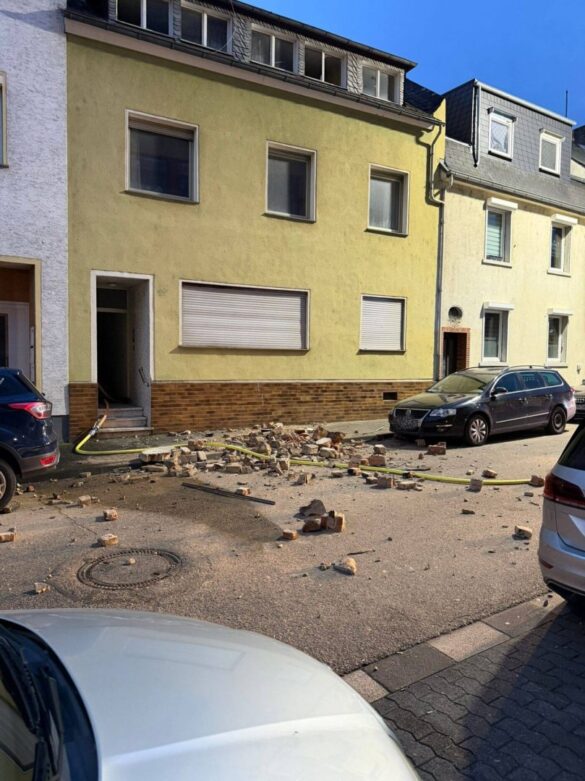 kamin-lahnstein-1-min_56aktuell Heruntergefallene Ziegelsteine auf einer Straße vor einem gelben Gebäude.