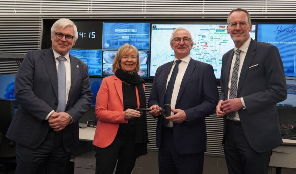 leitstelle-eroeffnung-18-min_56aktuell Vier Personen bei der Eröffnung einer Leitstelle mit Monitoren im Hintergrund.