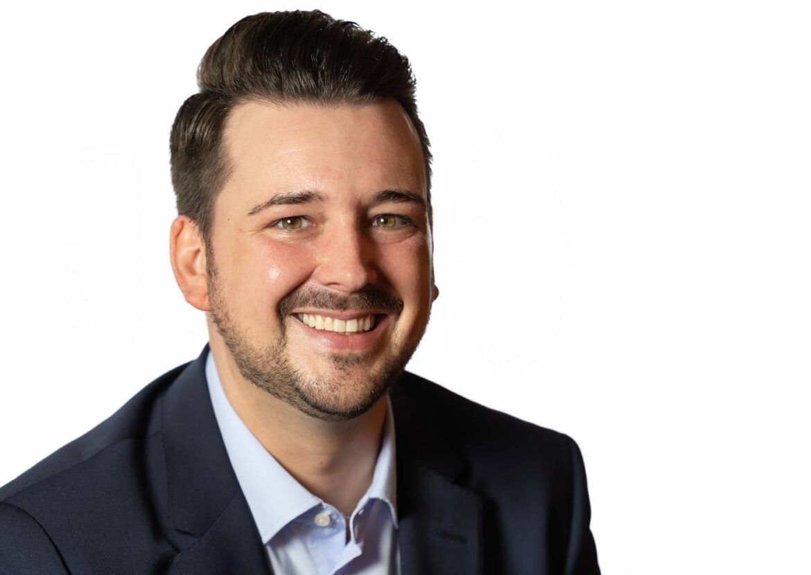 Porträt eines lächelnden Mannes im Anzug vor weißem Hintergrund