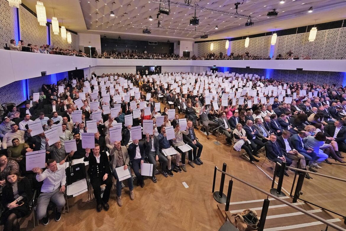 670 neue Handwerksmeister halten ihre Meisterbriefe in die Höhe.