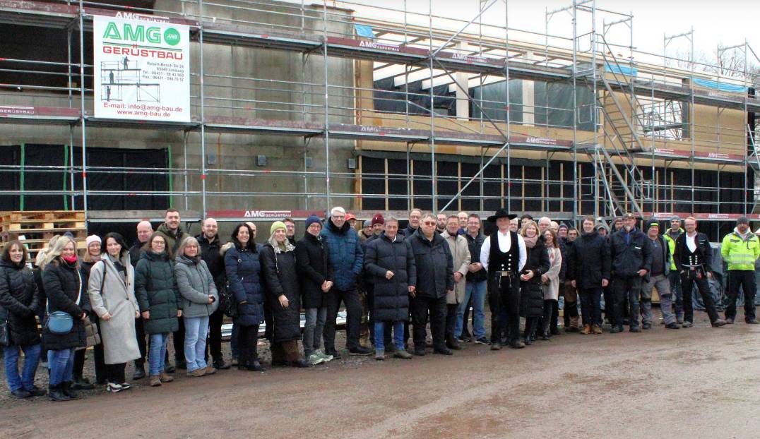Gruppe von Menschen beim Richtfest vor einem Schulneubau